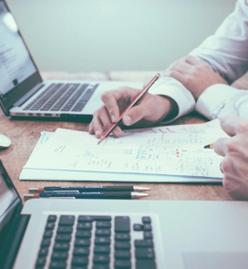 Person writing and using laptop