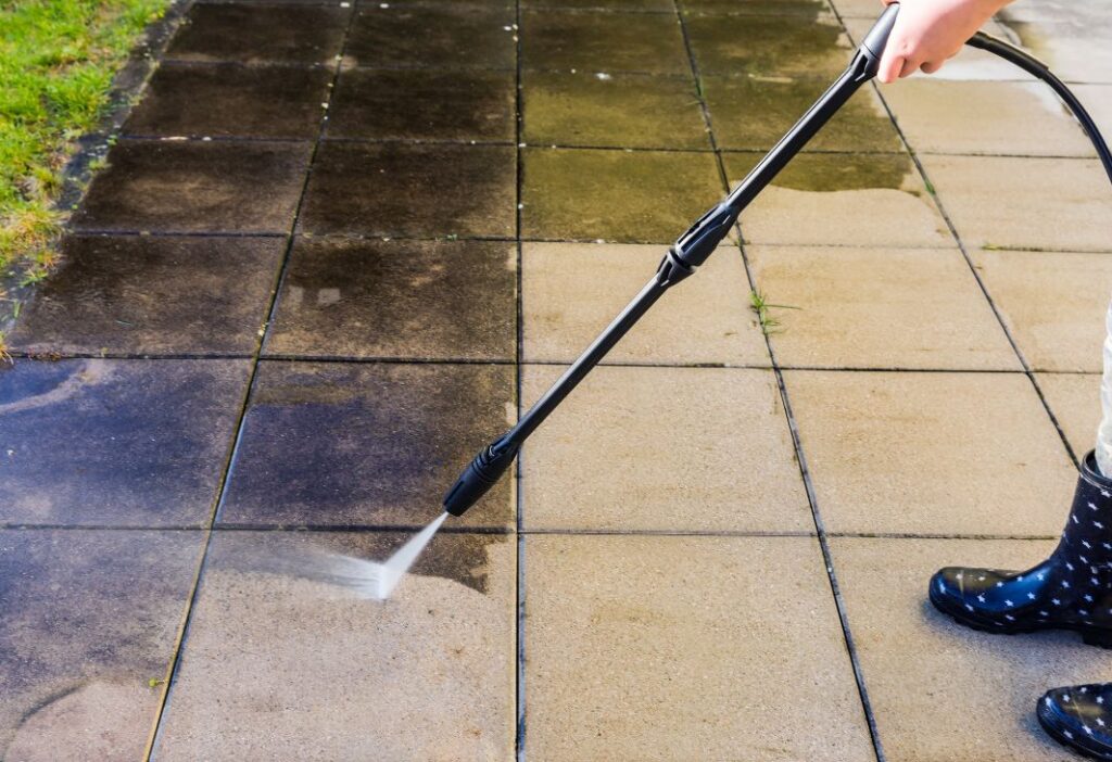 person cleaning the tiles with water pressure