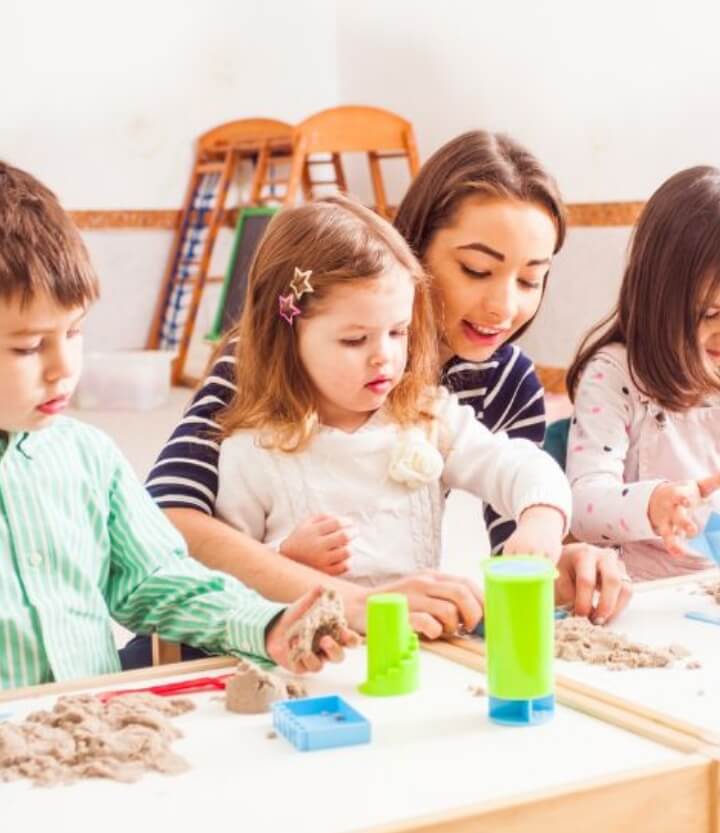 image of kids with their teacher playing with sands