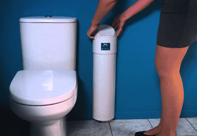 Person refilling a toilet with water using a water dispenser in a bathroom.